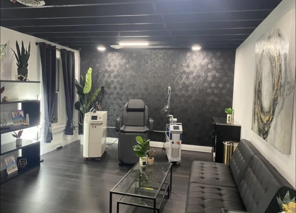 A view in side a laser tattoo removal studio with black, gold and white aesthetic and plants.