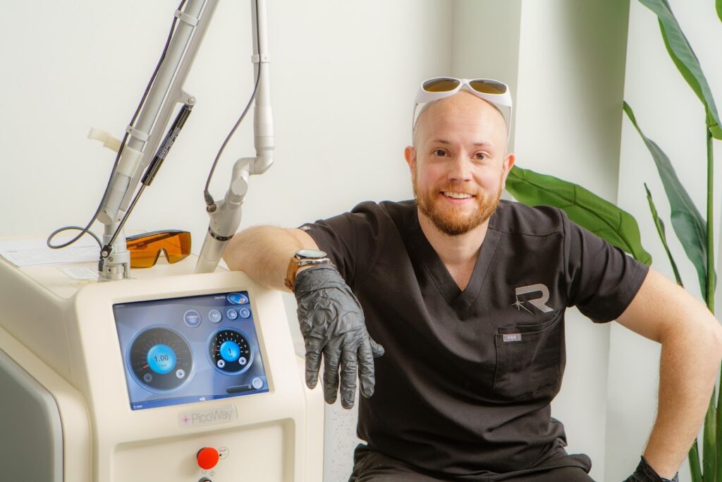 Laser tattoo removal expert next to a treatment device at Rethink clinic.
