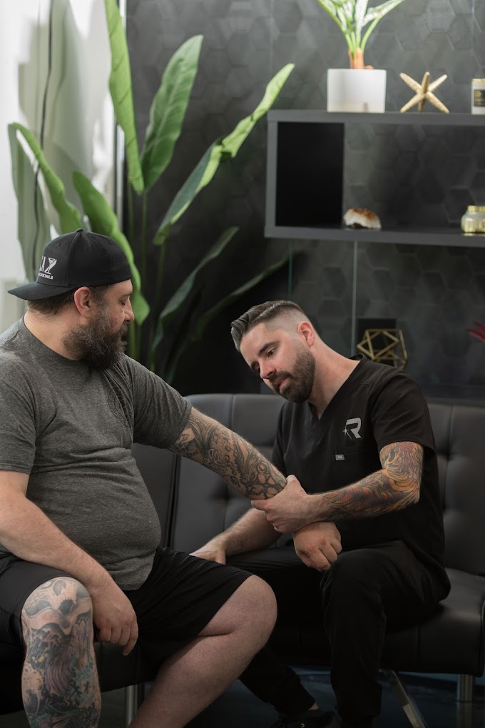 Laser tattoo removal provider consulting with client during tattoo evaluation.
