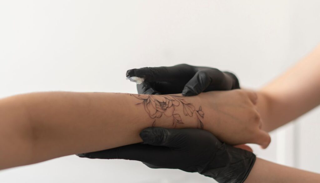 Technician applying ointment to fresh floral tattoo | Tattoo Removal Preparation